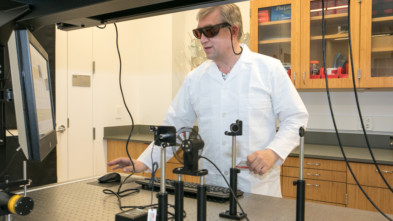 researcher in a lab coat working with laser equipment
