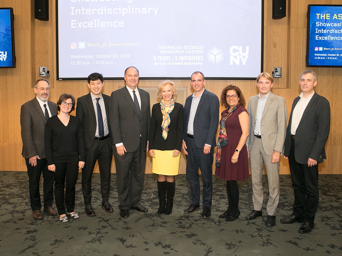 ASRC Initiative Directors, leaders, and CUNY faculty lstanding in front of presentation screen in the ASRC auditorium