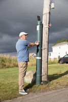 Apicture of Brett Branco standing near a FloodNet sensor.