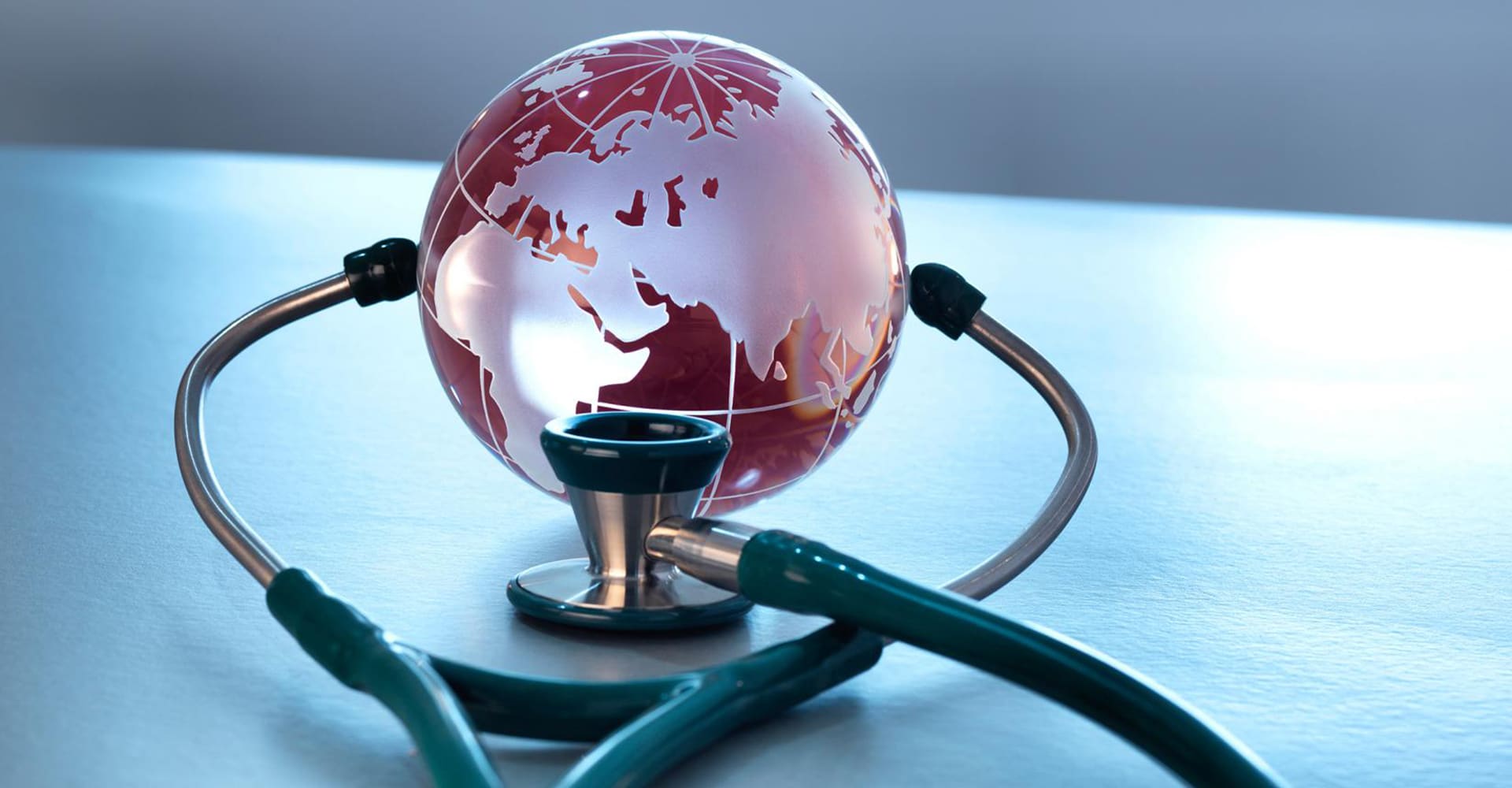 digital image of a stethoscope wrapped around a red glass globe on a light colored tabletop