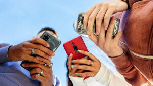 Low angle view of three young people using mobile phones outdoors.