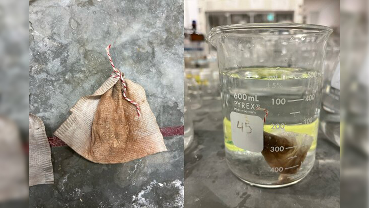 A tea bag with a red and white string next to a beaker of water containing a brown substance labeled "45."