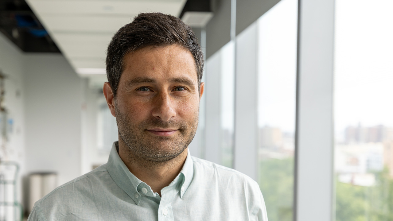 Professor Gabriele Grosso standing by a window and smiling.