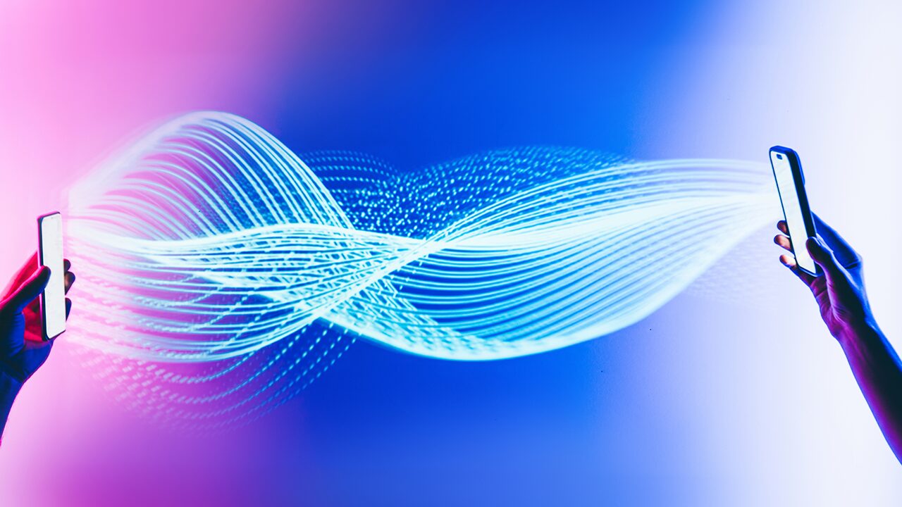 Two hands holding smartphones, with a glowing wave of digital lines connecting them against a gradient background.