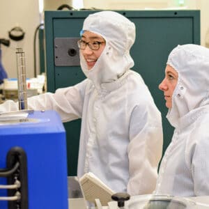 two researchers in cleanroom suits working in the deposition bay of the nanofabrication facility