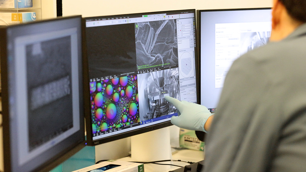 Scientists at the ASRC pointing to computer monitors with data on the screen