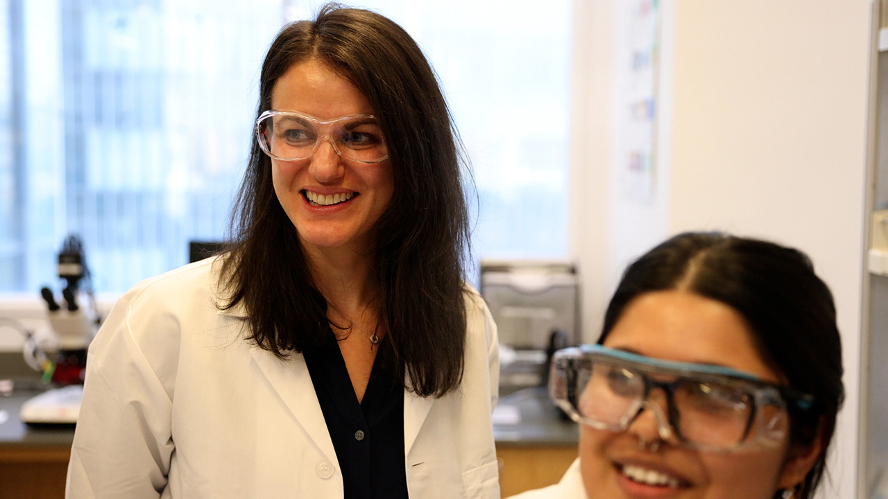 Prof Shana Elbaum-Garfinkle and a student in the lab wearing protective goggles and lab coats