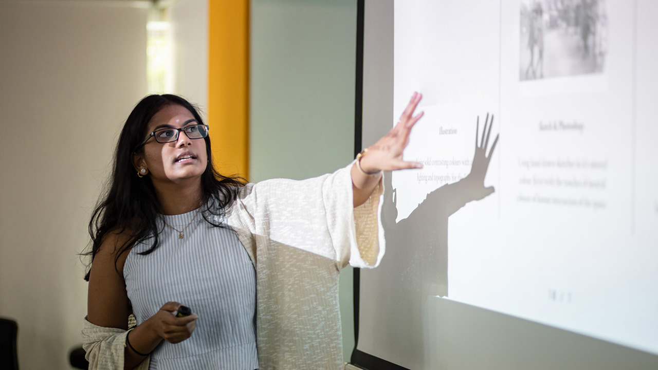 A student giving a presentation in front of a projector screen.